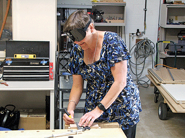 Connie uses power tools in the BISM woodworking shop