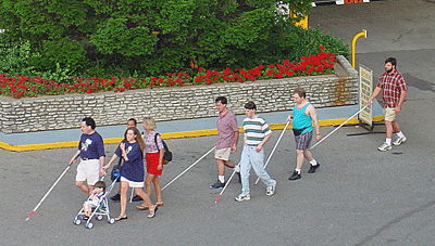 A group of people with canes walking outside.
