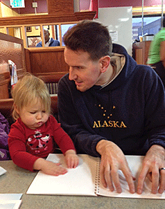 Jesse Hartle of Maryland, a blind father, reading a Braille book to his daughter.