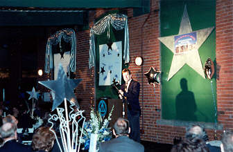 Frank Luntz stands speaking at the podium he is surrounded by balloons and other decorations.