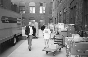 Mr. Cheadle and David Maurer walk past the boxes that are ready for loading into trucks in the courtyard at the National Center for the Blind.