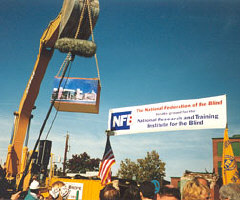 The track hoe lifts the box out of the ground before lowering it onto the stage.
