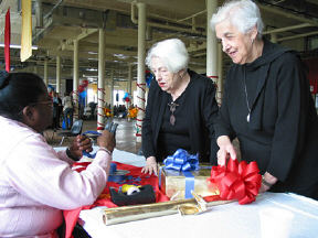BISM volunteer Annette Gordon teaches Lillian Levine and Violet Zlotowitz how to make decorative bows at the gift wrapping booth.