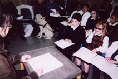 Harriett Go reads a story about Louis Braille to the students of St. Lucy's School.  Both she and the students are using Braille.