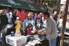 Steven Booth, Greater Baltimore chapter member, uses plastic golf balls in a six-egg carton to quiz two young sisters on the Braille alphabet at a local street fair.