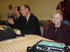 Jim McCarthy, Jim Gashel, and Diane McGeorge sit at the head table during the opening meeting.
