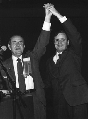 Kenneth Jernigan and Marc Maurer raise linked hands on the podium at a national convention.