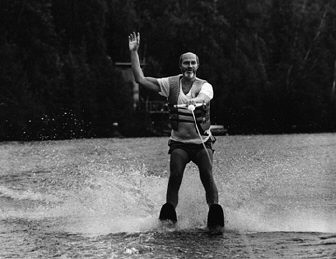 A young Jim Omvig glides across a lake on waterskis