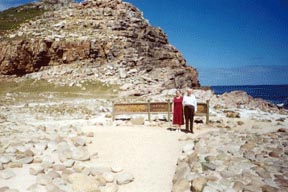 The sign behind the Pierces announces the latitude and longitude of the Cape of Good Hope.  The Atlantic can be seen on the right.