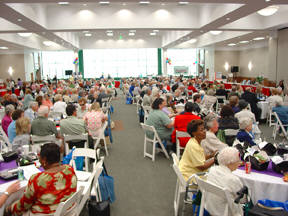 Crowd seated at Possibilities Fair 2004 eating boxed lunches