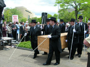 Six pall bearers carry the casket containing the Grim Reaper away from the rally.