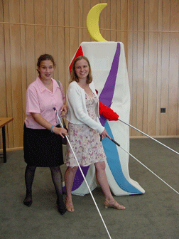 Tai Tomasi (left) and Stacy Cervenka (right) pose in front of Whozit, copying his cane-extended stance.