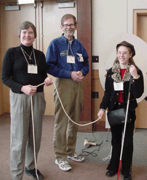 Three people stand together holding a rope for a demonstration.