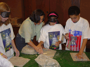  Anne Cunningham helps three students mold clay.