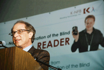 Ray Kurzweil addresses the crowd with the banner behind him.