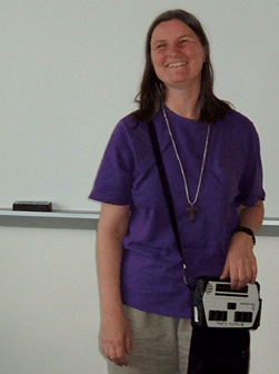 Sheri Wells-Jensen stands in a classroom holding her electronic Notetaker.