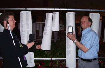 Jennifer Dunnam and Steve Jacobson use their Kurzweil�National Federation of the Blind Readers to identify and read the Minnesota registration report outside the ballroom at the NFB convention. They have never before been able to read this information independently.