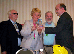 Charlie Allen (left) and Kevan Worley (right) present an award to Don Morris while Shirley Morris reads the inscription.