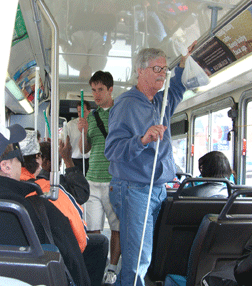 Bob Gardner uses his white cane to find an empty city bus seat.