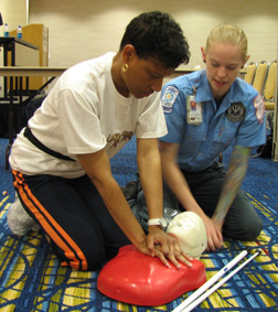 Denice Brown of Philadelphia practices CPR on a dummy while an instructor looks on.