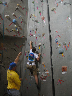 Student Mika Baugh (Indiana) begins to climb the 30-foot rock climbing wall at the Johns Hopkins rec center while mentor Michael Edwards (Missouri) acts as her belay.