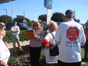 Commissioner Fernandez reads aloud the Orange County White Cane Safety Day proclamation that she presented to the blindness groups represented at the demonstration. In the foreground is a close-up of the back of a T-shirt that reads, �STOP! IT�S THE LAW, Central Florida�A White Cane Community.�
