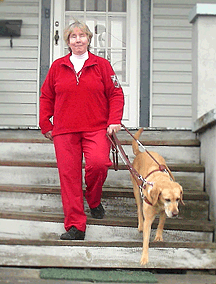 Judy Jones walks down the steps outside her home with her guide dog.