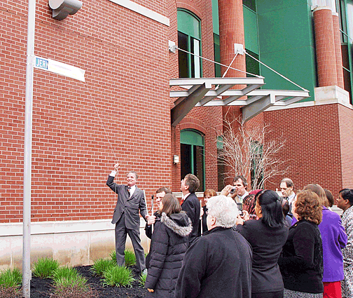 President Maurer unveils the street sign outside the Jernigan Institute with members of the staff looking on.