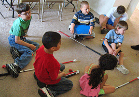 Campers sit on the floor listening to their teacher.