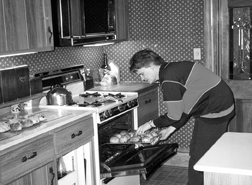 Barbara Pierce lifts the Thanksgiving turkey from the oven back home in Oberlin. This photo appeared in the original story in the Kernel Book, Wall-to-Wall Thanksgiving.