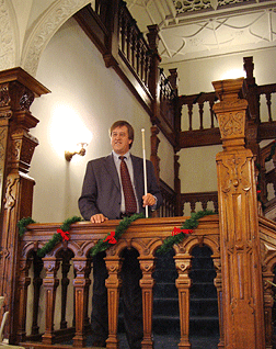 Al Spooner stands on the landing of the carved staircase.