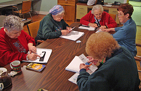 Joyce Scanlan (right) teaches Braille to her class of seniors meeting in the Pillsbury family room at BLIND Incorporated.
