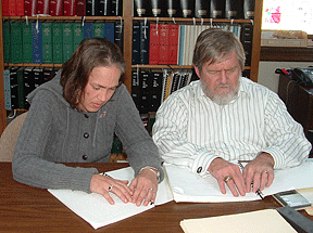 Jerry Whittle sits at a table with Amy Weaver, who is reading a Braille book. CAPTION: Jerry Whittle works with Amy Weaver on Braille.