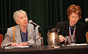 Sharon Maneki speaks into a mic with resolutions committee secretary Marsha Dyer beside her.