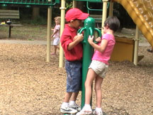 Alvin and Hadley, students in the NFB of Georgia BELL program, spin on playground equipment.