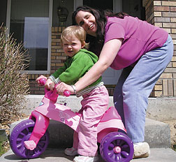 Jo Pinto pushes her toddler on a Big Wheel.