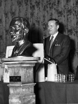 A bust of Jacobus tenBroek stands in front of Kenneth Jernigan making a speech at the podium during the 1969 national convention in Columbia, South Carolina.