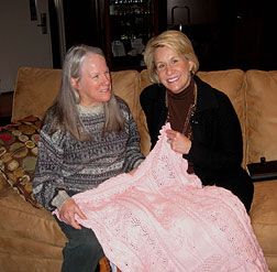 Donna Hill and Lyndall Stout sit on a couch with an afghan