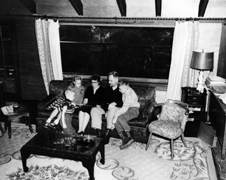 The tenBroek family seated on a sofa looking at a photo album.