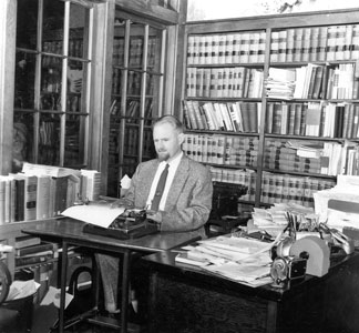 Dr. tenBroek sitting at his desk using a Braille writer.
