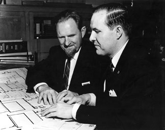 Jacobus tenBroek and Kenneth Jernigan seated at a desk examining building raised-line blueprints. 