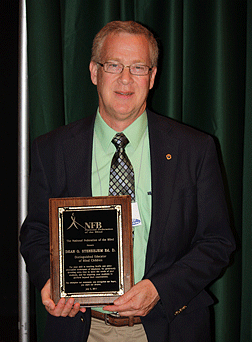 Dean Stenehjem holding his plaque