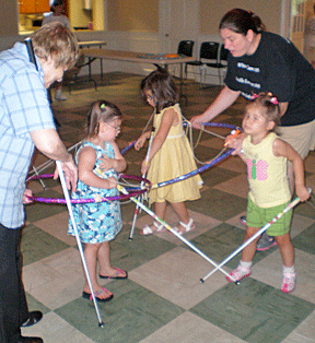 Ms. Nancy and Ms. Casey show the younger kids what it is like to be in a traffic jam while remaining in their own bubbles formed with Hula Hoops. Kylie, Batya, and Lydia use their canes and their bubbles to learn about personal space.