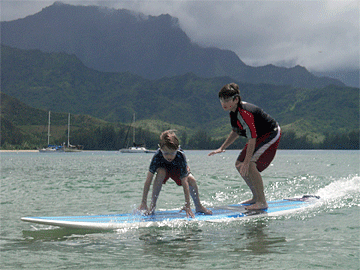 Tandem-surfboarding brothers, Vejas and Petras, riding the same surfboard at the end of their run