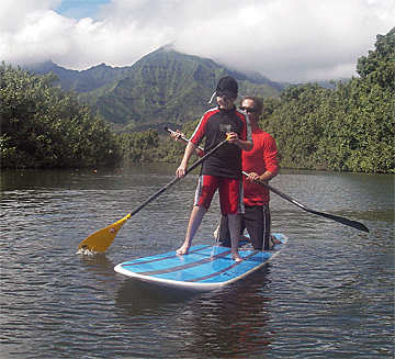Paddleboarding instructor Karlos takes a brief break while Vejas paddles down Hanalei River.