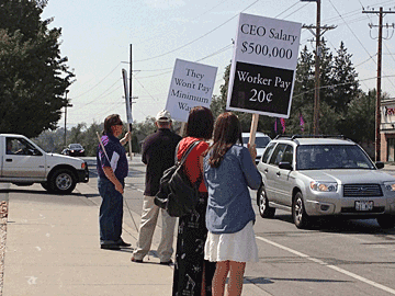 Everette Bacon, Ron Gardner, Evelyn Trujillo, and Karina Trujillo hold signs for the view of passing traffic.