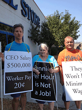 Tony Schnurr, Karen Hamric, and Joe Higdon pose with picket signs around their necks. A Goodwill store can be seen behind them.