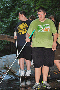 Matt Pettiet and Mark Meyers use their canes to find rocks for crossing a stream.