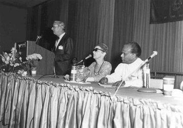 Robert L. Hunt (May 22, 1924, to July 20, 2012), stands at the podium during the 1971 convention of the National Federation of the Blind in Dallas. To his left are Isabelle Grant of California and internationally known Rienzi Alagiyawanna from Ceylon, who was then first vice president of the International Federation of the Blind.