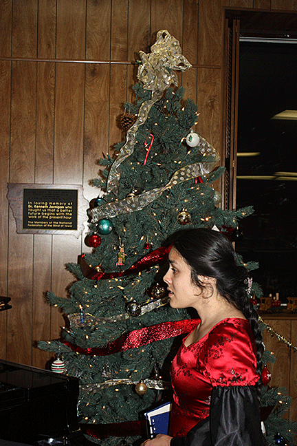 Jessica Bachicha-Ewell sings in front of the Christmas tree.